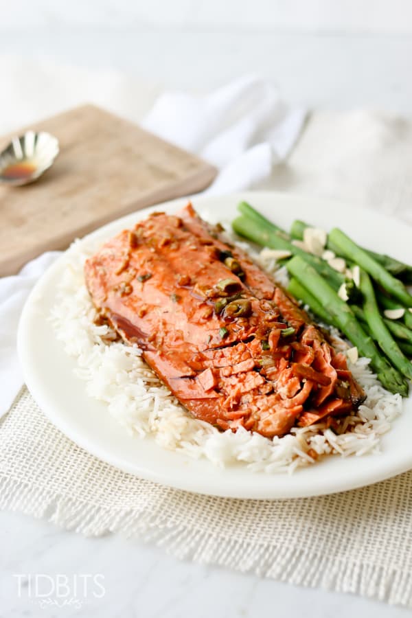 Teriyaki salmon served on a white plate with rice and vegetables
