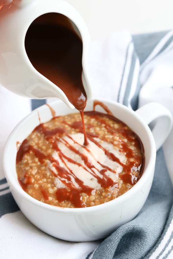 Steel Cut oats in a white bowl topped with chocolate syrup