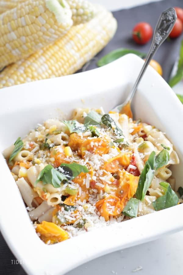 A close up of Sweet Corn and Tomato Pasta in a square white bowl