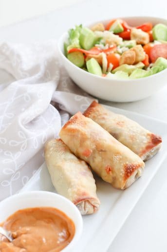 Pepperoncini Beef Egg Rolls on a white serving plate with dip