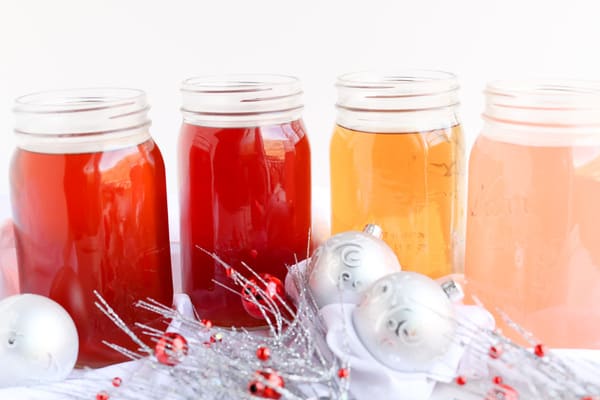 Four jars of holiday infused water with christmas decorations
