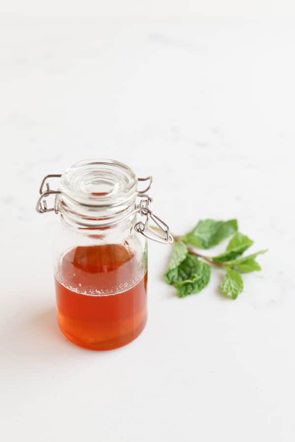A jar of honey next to a mint leaf