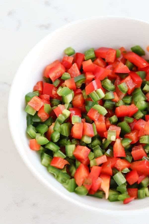 Diced red bell peppers and jalapenos in a white bowl