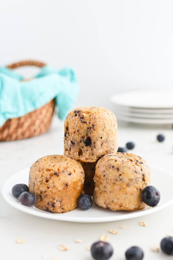 Three blueberry oatmeal muffins stacked on a white plate