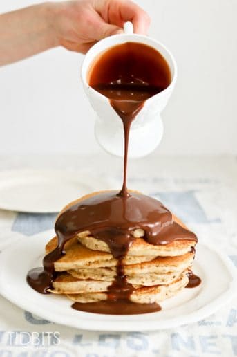 Sauce being poured over multigrain pancakes
