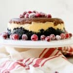 A triple chocolate cheesecake on a cake stand with fruit