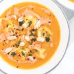 butternut squash soup in a white bowl with peanuts and basil