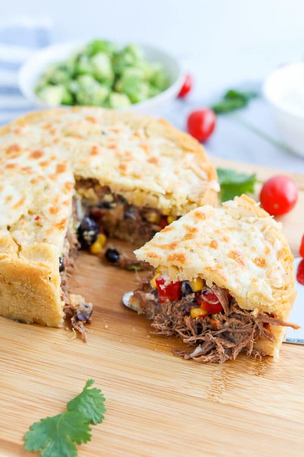 Slice of Tamale pie with meat and veggies on a wood cutting board