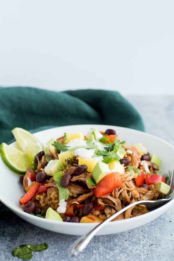 jerk chicken in a bowl topped with tomatoes, yogurt, and avocados