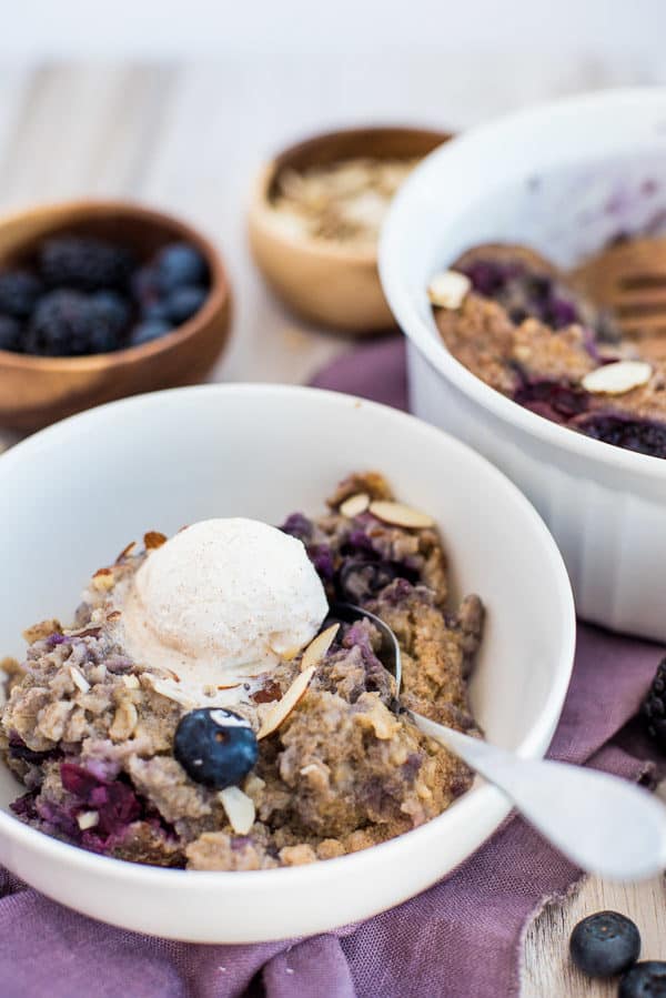 blueberry oatmeal in a white bowl with cream on top