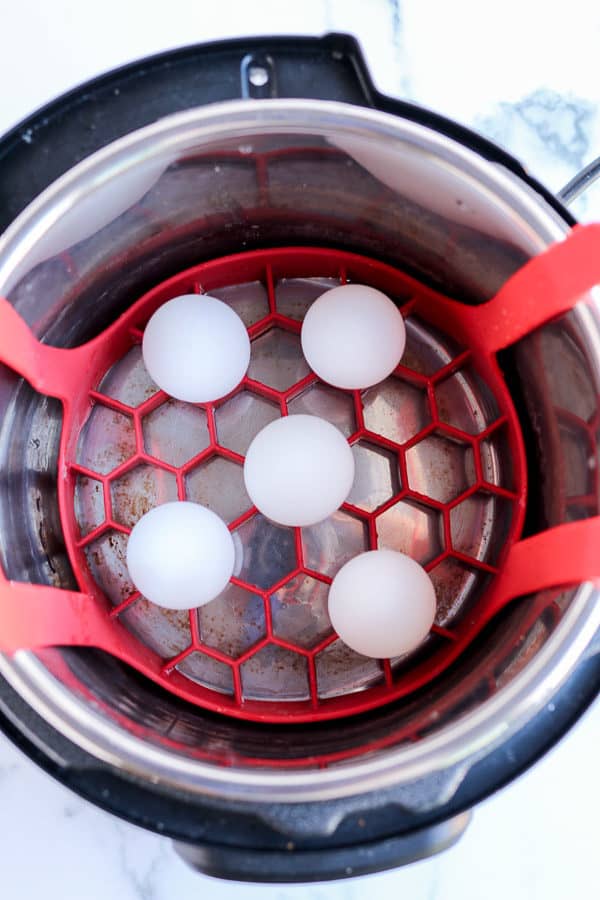 hard boiled eggs on a red rack inside the pressure cooker