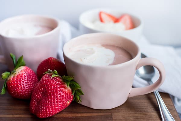 Instant Pot Strawbery Crio Bru in a pink cup with cream on a wood board with strawberries