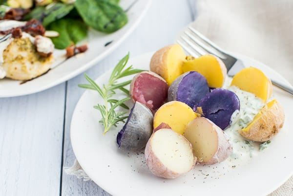 Purple, yellow, and white potatoes on a white plate with a creamy sauce