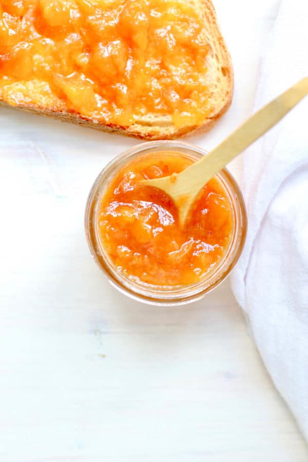 Peach jam in a jar with a spoon and white napkin