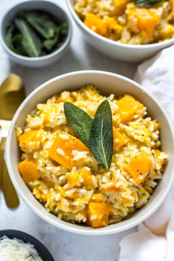 butternut squash risotto in a white bowl with sage leaves