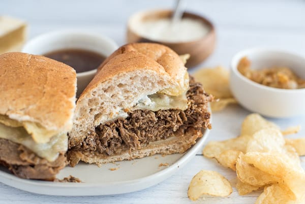French dip sandwich on a plate with chips and horseradish sauce