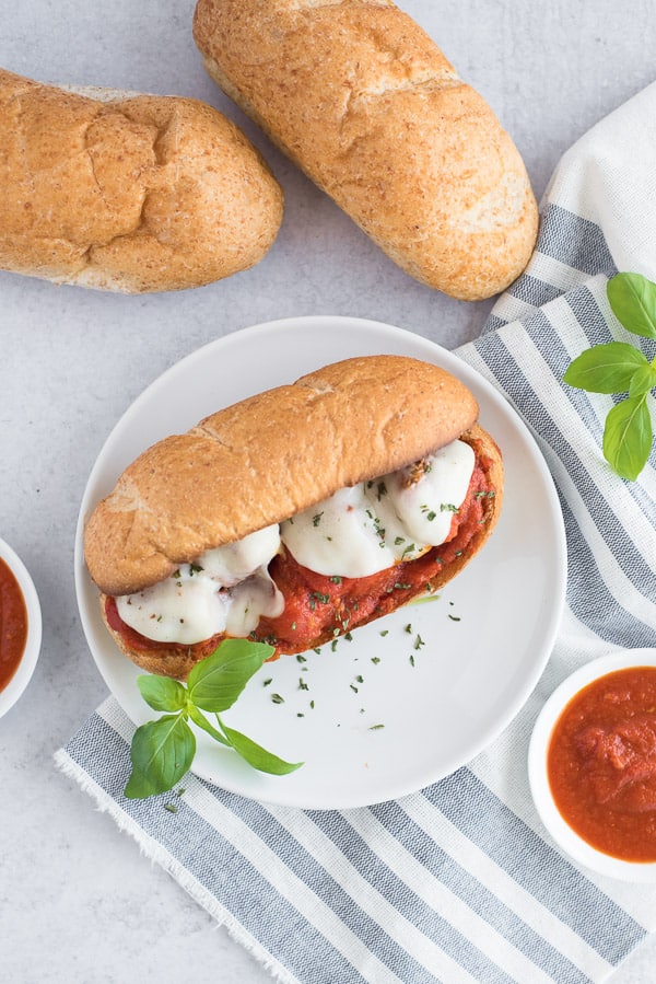 meatball sandwich on a white plate with basil