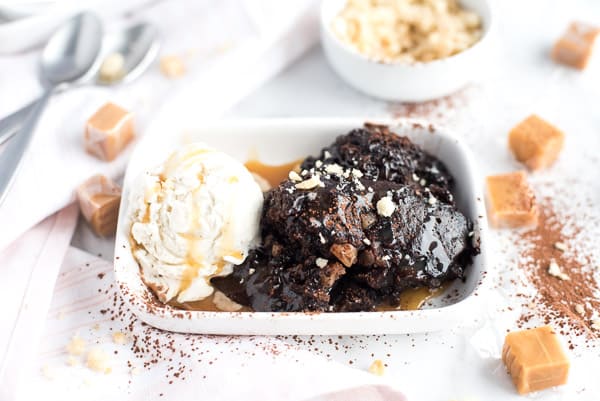 Brownie pudding in a white bowl with ice cream and caramel sauce