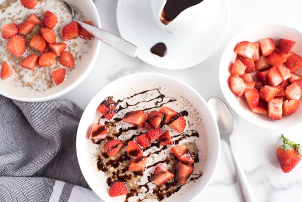 2 bowls of oatmeal, one with strawberries and chocolate and one with just strawberries