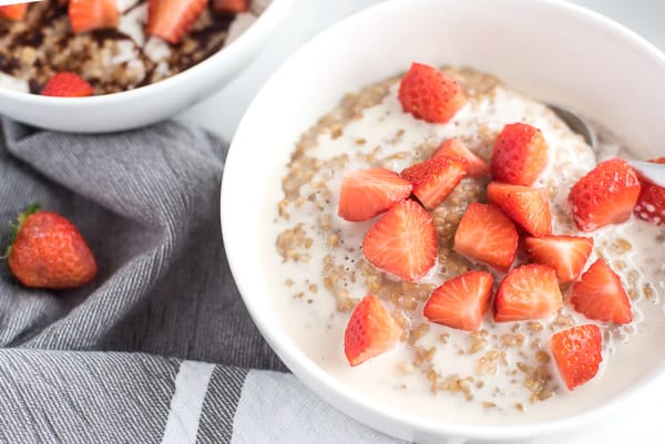 Bowl of oatmeal with fresh strawberries on top in a white bowl
