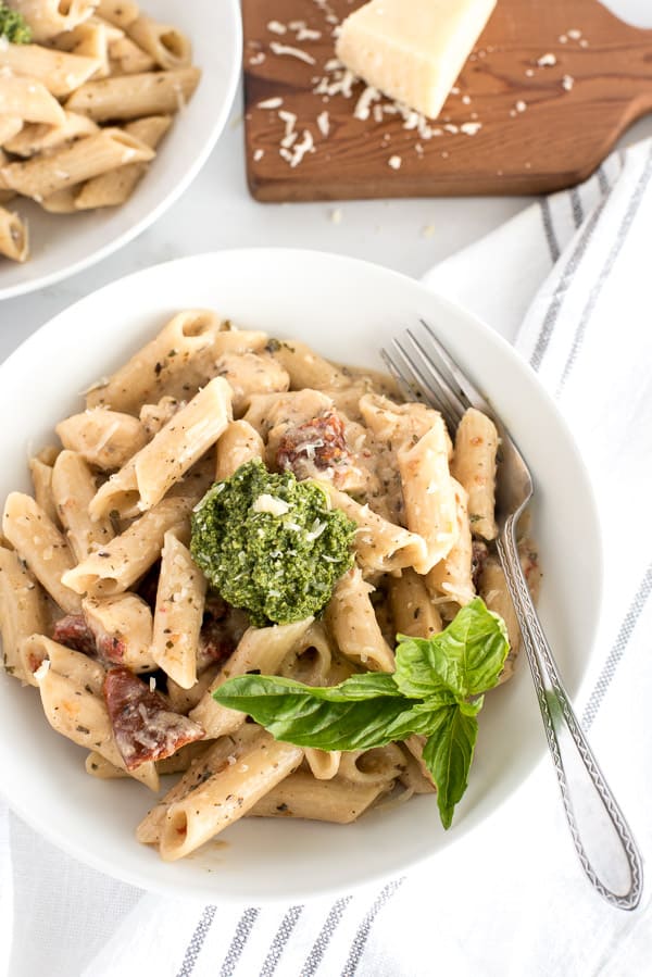bowl of pasta with sun-dried tomatoes and pesto and basil