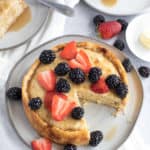 Giant pancake with a slice on a white plate with berries