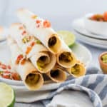 pile of breakfast taquitos with salsa and guacamole