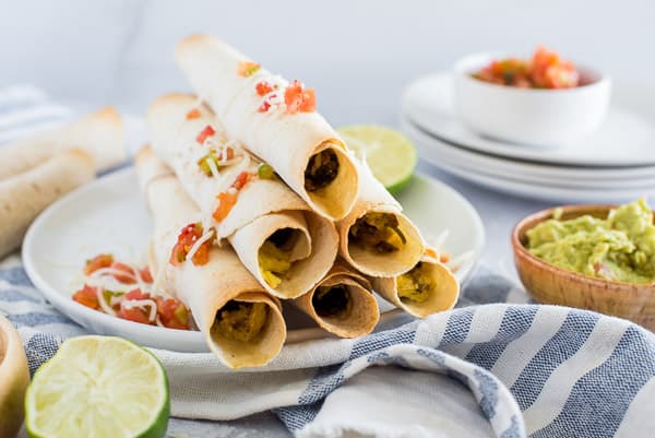 pile of breakfast taquitos with salsa and guacamole