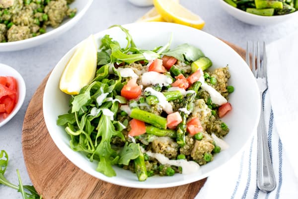 white bowl of chicken, quinoa, and vegetables with lemon slice
