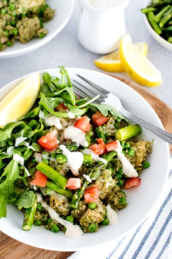white bowl of chicken, quinoa, and vegetables with lemon slice
