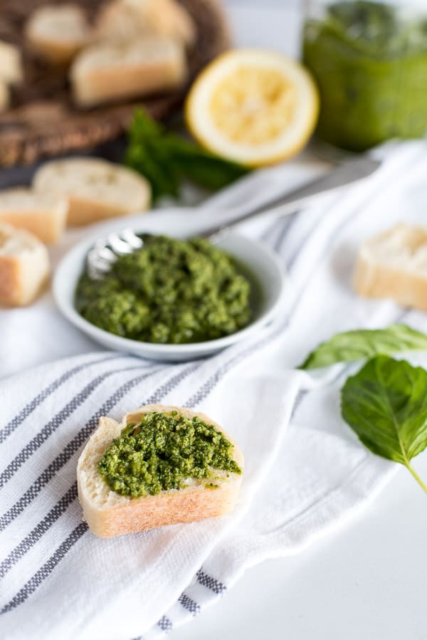 bowl of pesto and a slice of bread with pesto on top