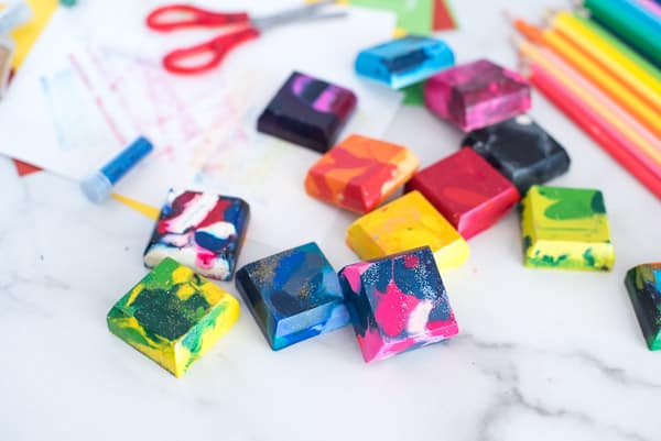 Square crayons of many different colors with scissors and paper