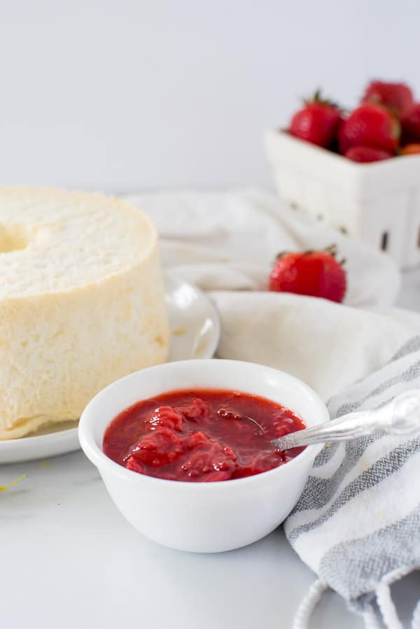 bowl of strawberry sauce next to angel food cake