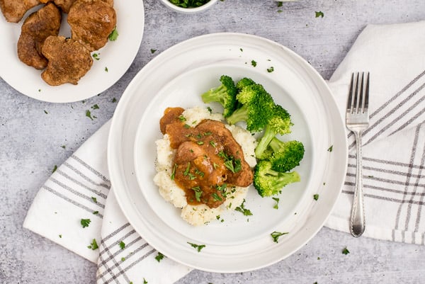 Pork chops and apricot sauce on a bed of mashed potatoes with broccoli