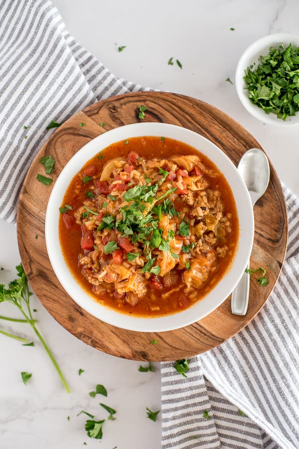 cabbage roll soup in a white bowl with a garnish of herbs