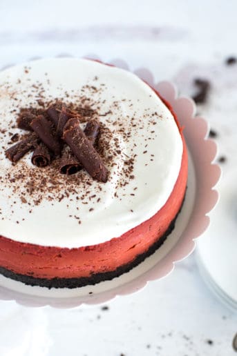 red velvet cheesecake on a white plate with chocolate curls