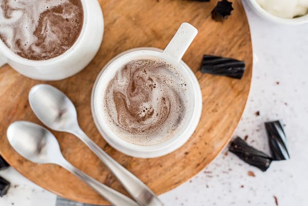 chocolate drink in a white cup with a spoon and cream