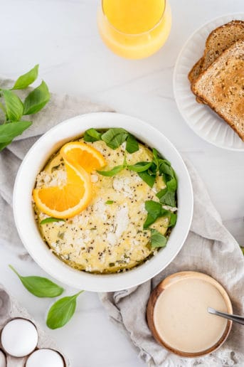 Instant Pot Spring Frittata in a white dish topped with herbs and an orange slice