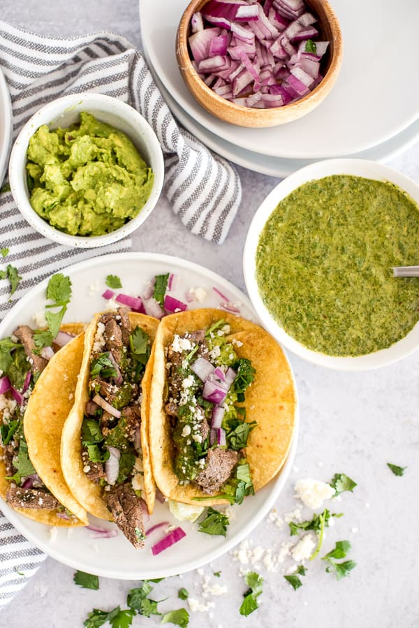 steak taco with a side of chimichurri sauce topped and guacamole