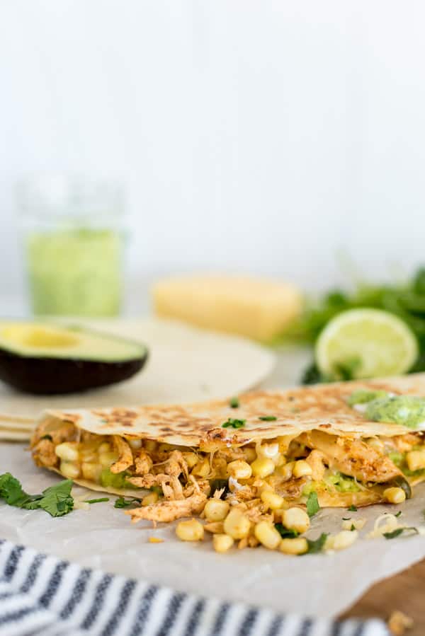 street corn quesadillas with avocado on a cutting board with lime