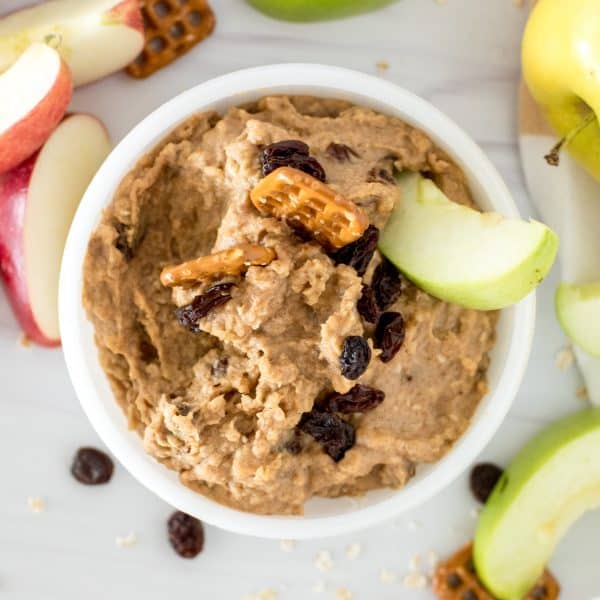 white bowl of oatmeal raisin cookie dough dip with apple slices