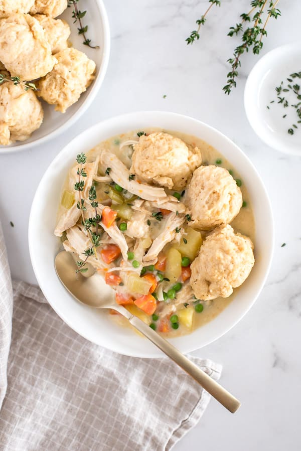 Instant Pot chicken and dumpling soup in a white bowl with a spoon