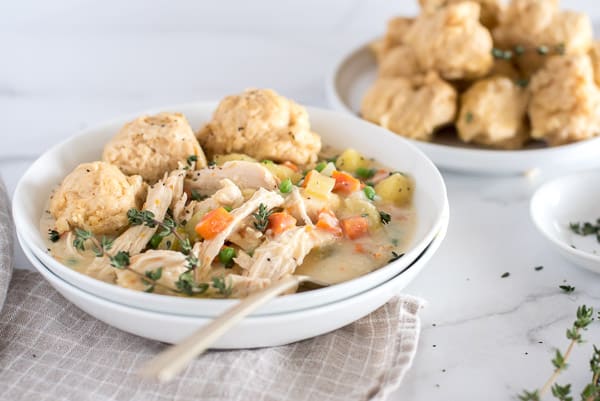 Instant Pot chicken and dumpling soup in a white bowl with a spoon