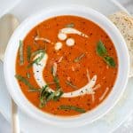 Tomato soup with cream and basil in a white bowl
