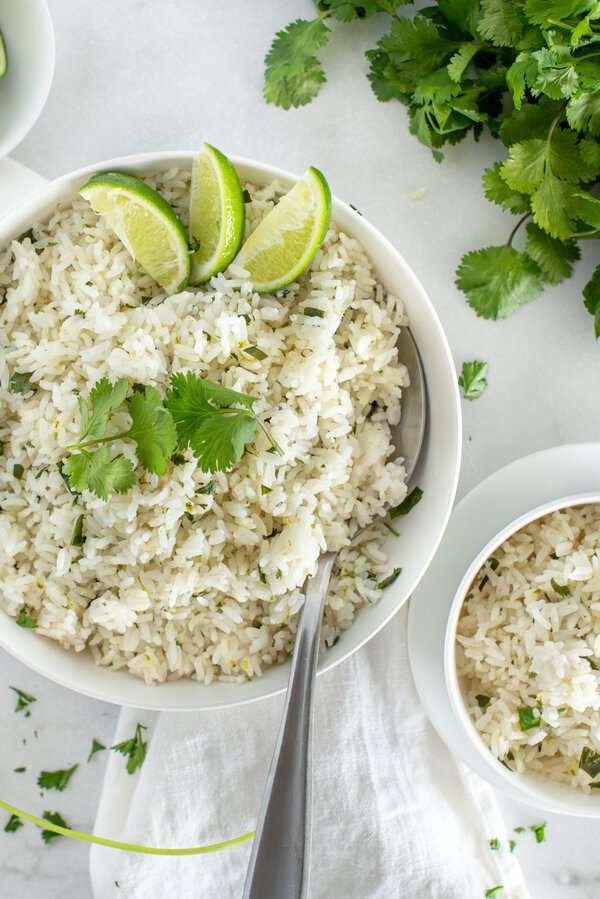 Cilantro lime rice in a white bowl with lime wedges
