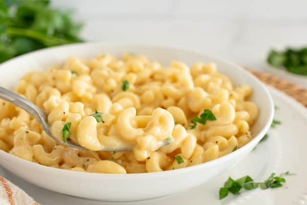 creamy mac and cheese in a white bowl with a fork