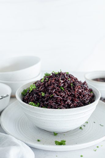 Black rice in a white bowl with a garnish of cilantro