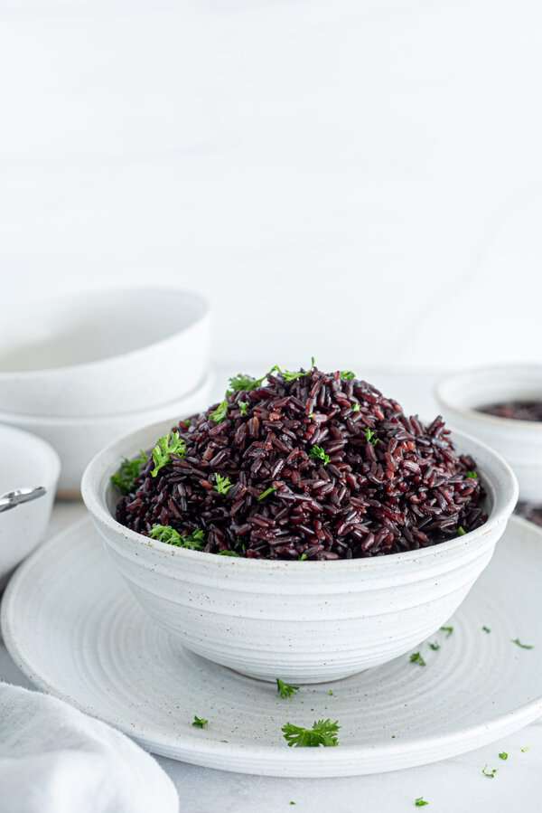 Black rice in a white bowl with a garnish of cilantro